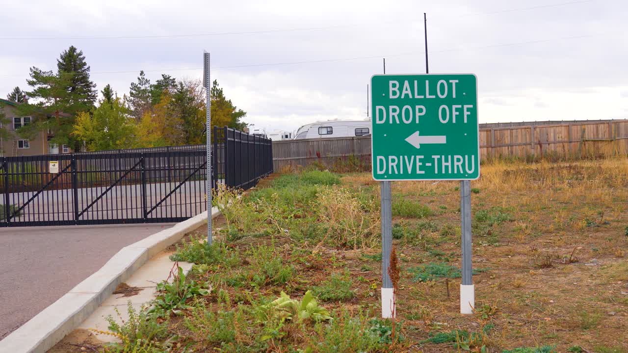 An election ballot drop-off sign with an arrow stands along a roadside, directing voters to the secure ballot box, representing civic engagement, democracy, responsibility, and voting accessibility