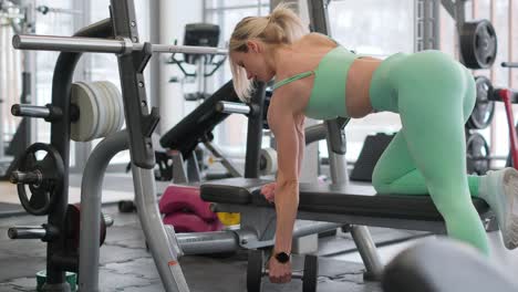woman doing dumbbell rows in gym