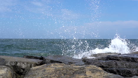 slow motion video of the waves from the ocean breaking over the rocks on the shore