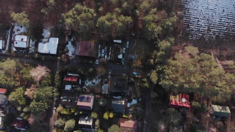 Drone-top-down-of-Polish-Village-covered-in-snow-tilts-up-to-reveal-dense-forest