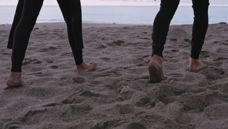 man in wetsuit walking on beach