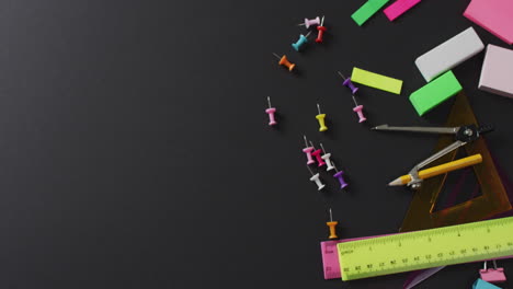 video of school supplies and notebooks, paper clips, pens over black background