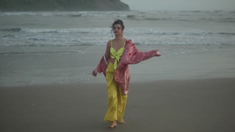 energetic woman running on the beach in slow motion with a pink dupatta and yellow outfit