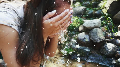 Young-woman-washing-face-in-spring-water.-Mountain-creek-with-clear-water