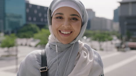 portrait of beautiful young muslim woman student smiling confident at camera listening to music using earphones wearing hajib headscarf