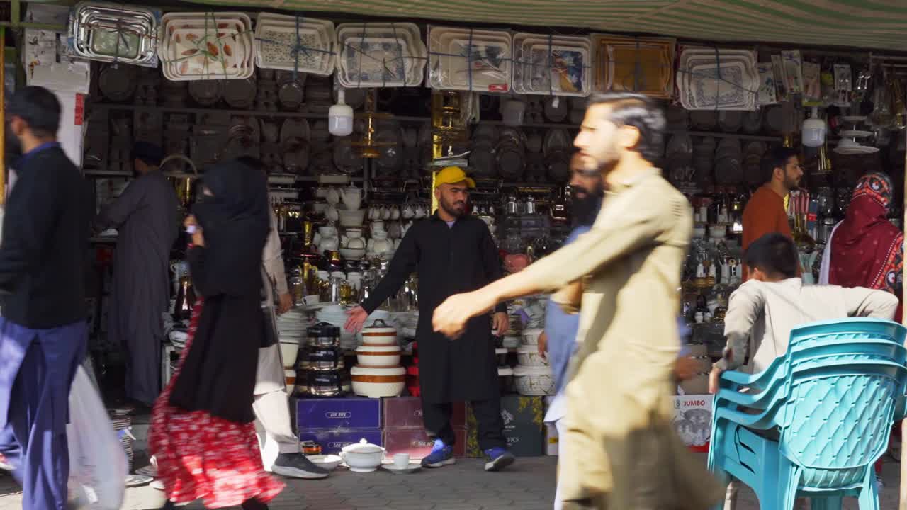 Vibrant market atmosphere in Islamabad with crowds of people bustling around street vendors and stalls to purchase crockery.