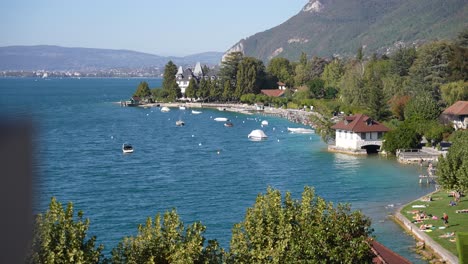 Boathouse-and-lake-shore-buildings-in-Lake-Annecy-French-Alps,-Wide-stable-shot