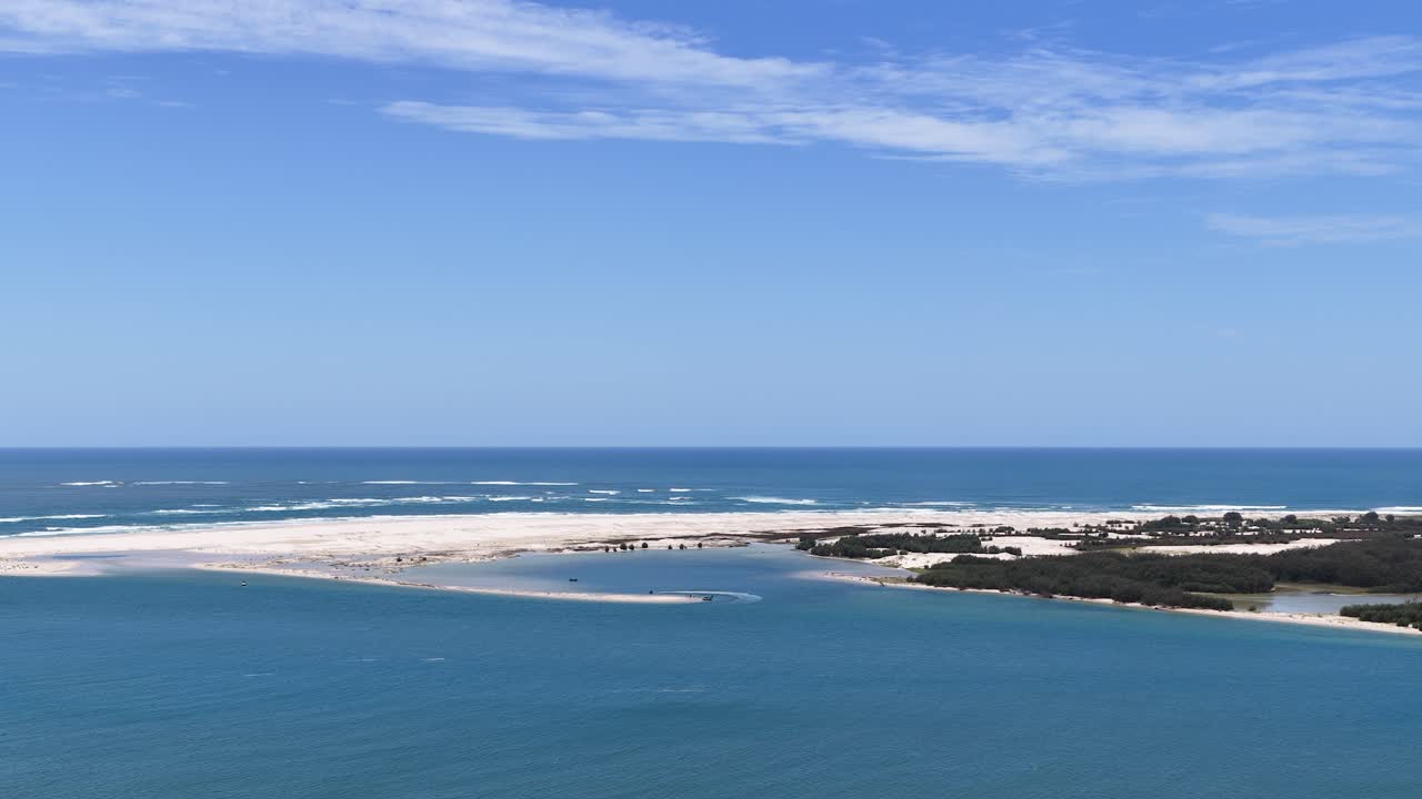 Foto aerea ad angolo elevato dell'acqua turchese dell'oceano che incontra banchi di sabbia bianca sotto un cielo azzurro limpido