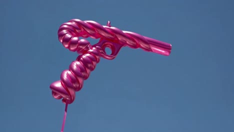 pink candy cane balloon gun against blue sky