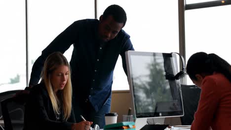 business colleagues interacting with each other at desk in office 4k