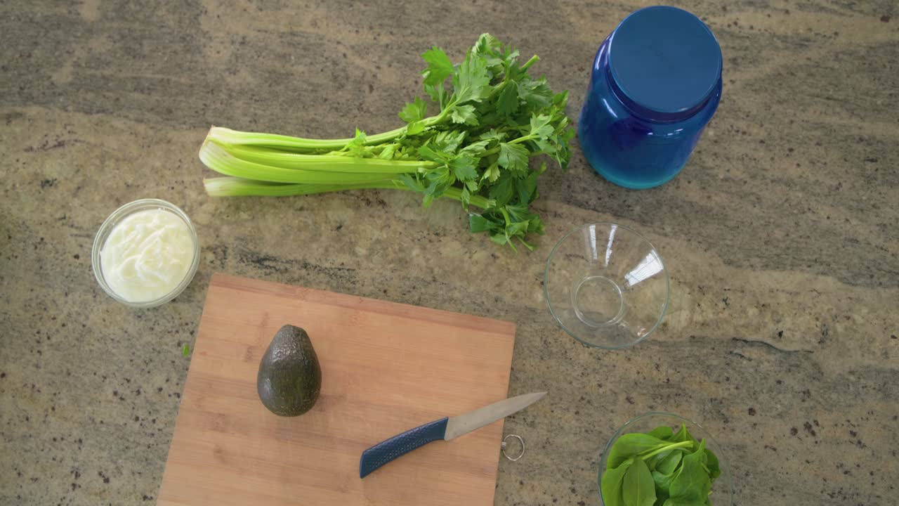 Camera is panning right, bringing avocado cutting board into center for food prep