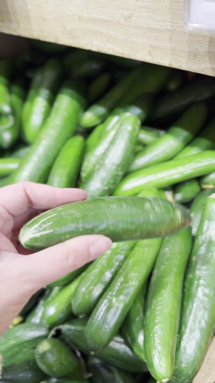 Person buying cucumbers at a grocery store