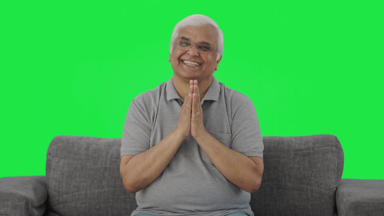 Happy Indian old man greeting and doing Namaste Green screen