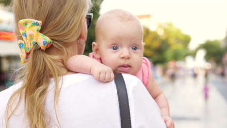 mum carrying baby and walking in city street