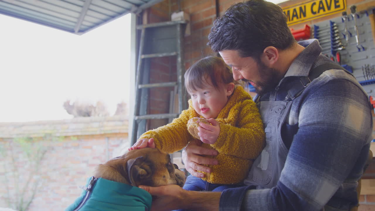 padre con síndrome de down hija acariciando perro mascota en el taller de casa