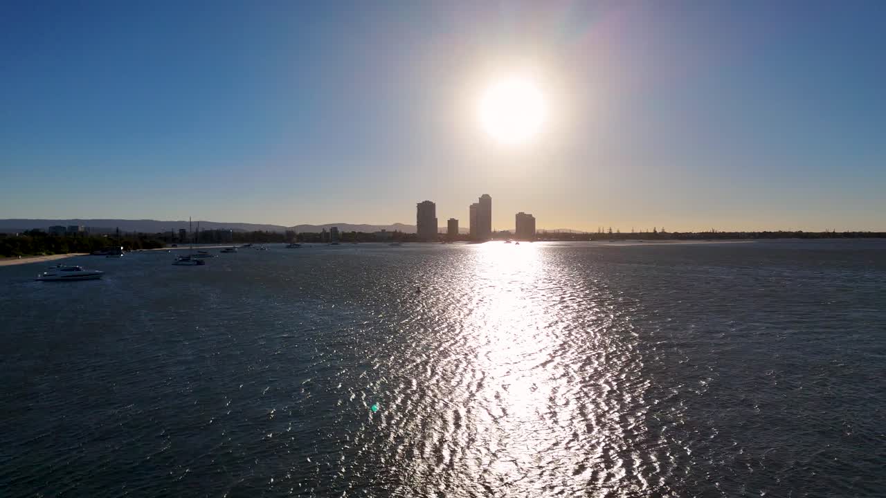 Aerial view of Gold Coast skyline at sunset, capturing shimmering water and silhouetted buildings under a clear sky