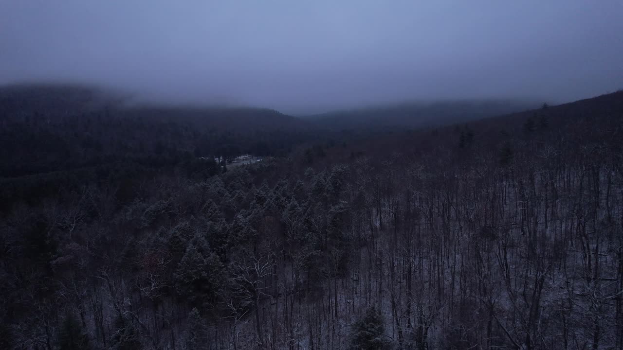Aerial drone video footage of a beautiful snowy, foggy evening with low clouds in the Appalachian mountains during winter