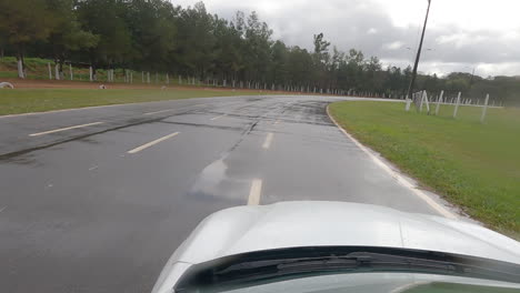 Cámara-Frontal-Que-Muestra-Un-Automóvil-Blanco-Conduciendo-En-Una-Pista-Privada