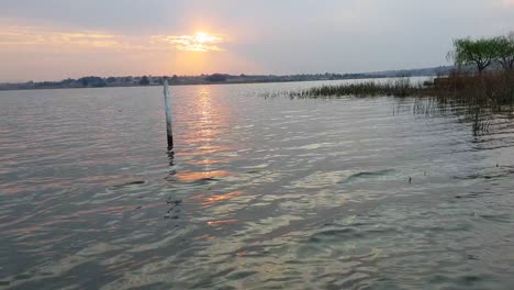 Puesta-De-Sol-A-Través-De-Unas-Pocas-Nubes-En-Un-Lago-Tranquilo-En-África