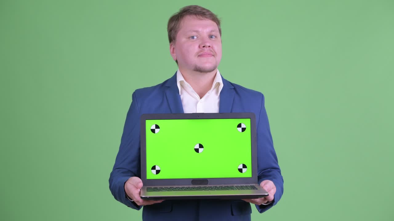 retrato de un hombre de negocios caucásico mostrando una computadora portátil con espacio de copia disparada contra un fondo verde