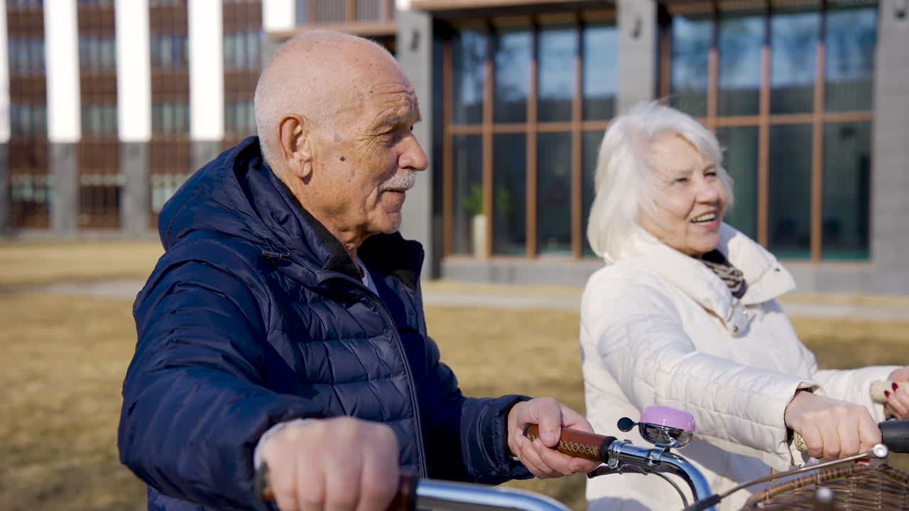 겨울날 공원에서 걷고 이야기하면서 자전거를 들고 있는 노부부의 모습