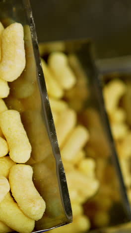 crispy corn snacks producing. crunchy yellow puffcorn moving on the conveyor. vertical video