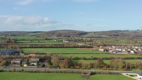 an ascending aerial shot revealing a bright lush green ireland countryside on a sunny fall day