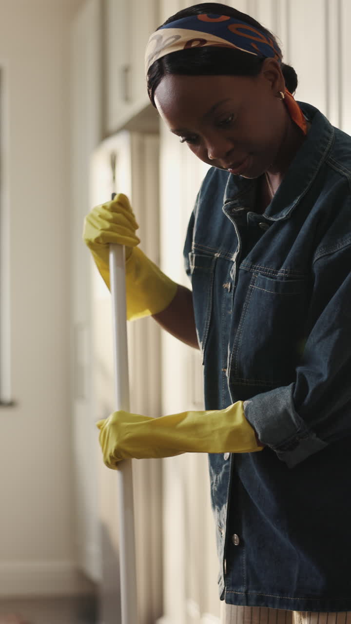 Mulher varrendo o chão de casa com luvas amarelas