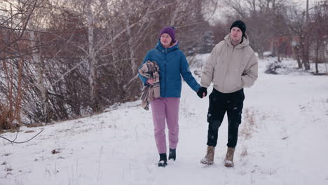 couple walking hand in hand in snowy park