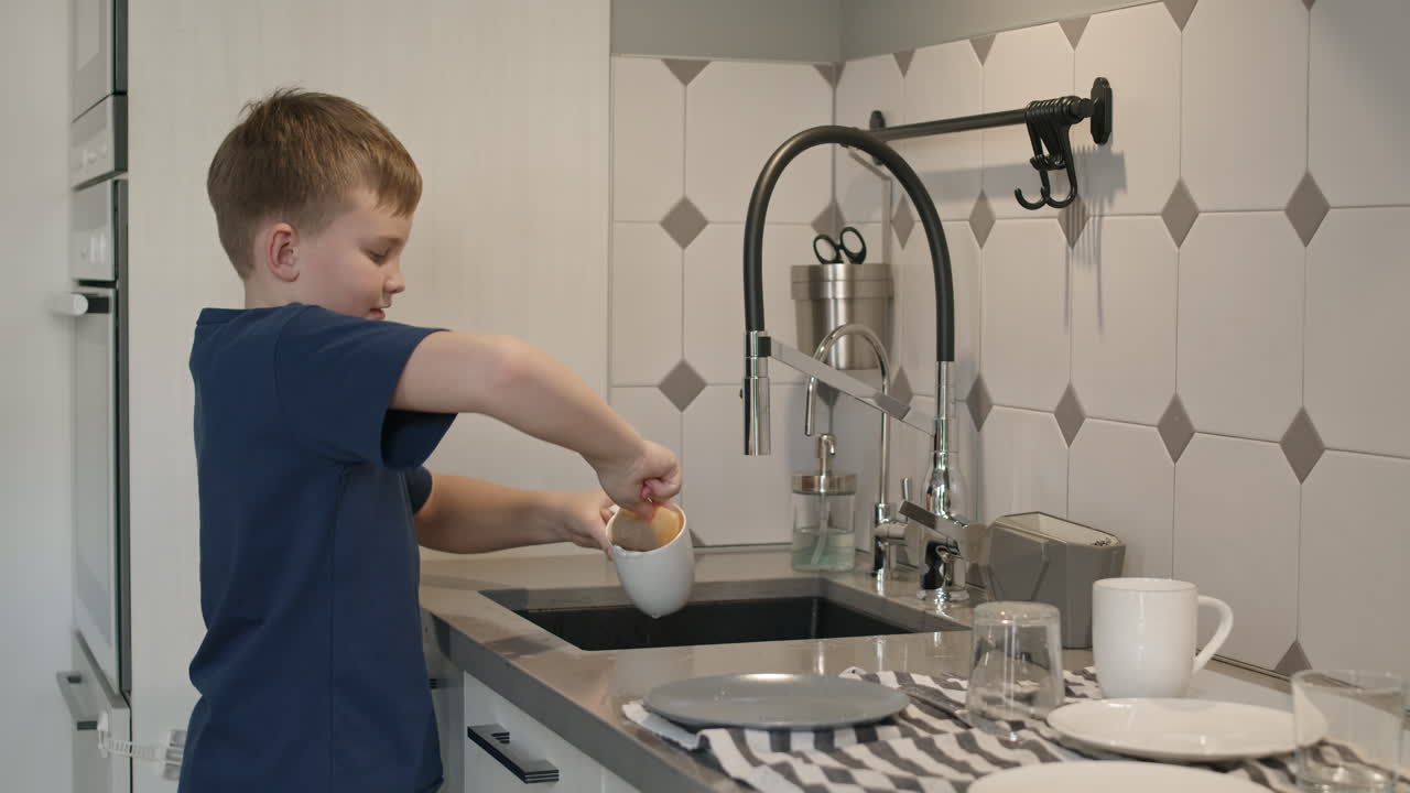 Niño lavando platos en una cocina moderna