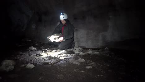 caver examining pile of bones from skeleton of extinct giant moa bird on floor of new zealand cave.