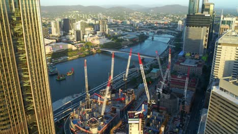 grúas torre en la parte superior del edificio queen&#39;s wharf brisbane en la orilla del río en la ciudad de brisbane, queensland, australia