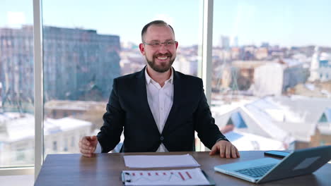 astonished businessman at workplace. smiling office worker sitting at the table with a laptop on window background with city view.