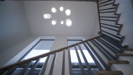 elegant staircase with contrasting wooden steps and metal railings in a bright, high-ceilinged home with decorative hanging lights