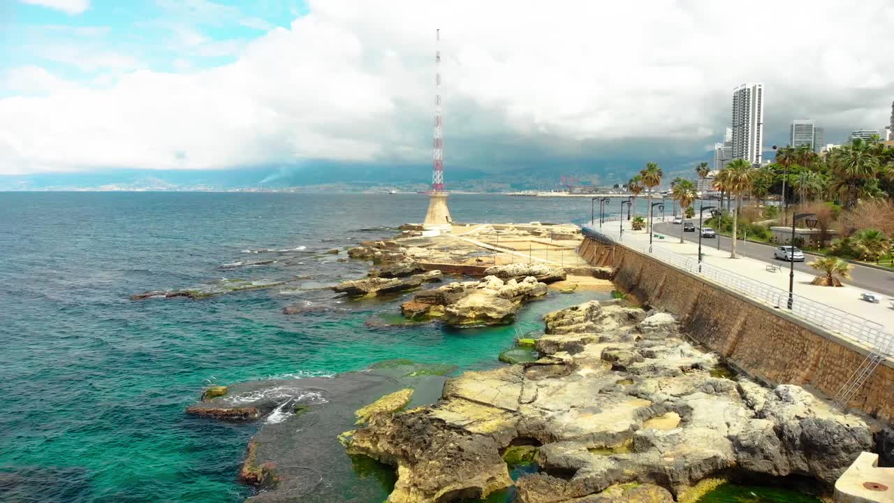 Dynamic aerial drone footage capturing Beirut&#x27;s Manara. Features the iconic lighthouse, crashing ocean waves against the shore, and the sprawling cityscape. A vibrant look at coastal Beirut.