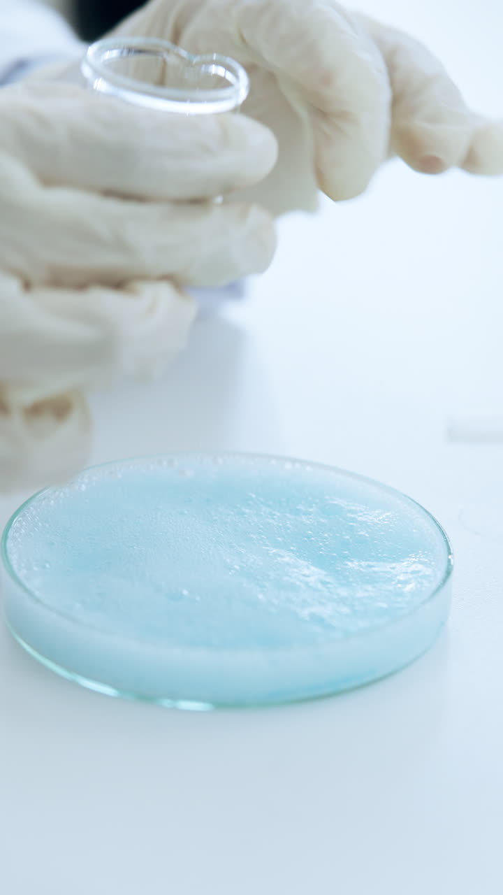 Scienziato che versa liquido blu su polvere bianca in una capsula di Petri