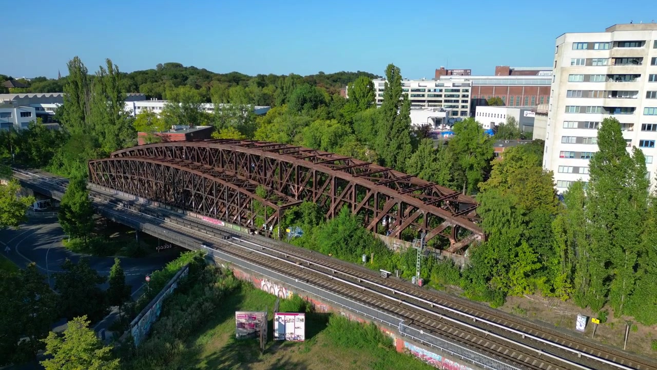 Liesenbrücke in Berlin, zeigt Eisenbahnschienen, Graffiti, Bäume und die umliegende Stadtlandschaft. Schöner aufsteigender Drohnenflug mit Luftaufnahme.