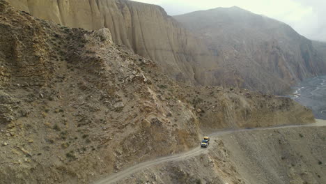 Toma-De-Drone-De-Un-Jeep-Safari-Viajando-A-Través-De-Un-Crucero-Todo-Terreno-En-La-Colina-Del-Desierto-De-Mustang-Nepal