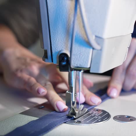 female hands working on tailoring. tailor working with sewing machine at fashion design workshop