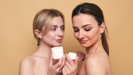 dos mujeres con productos para el cuidado de la piel