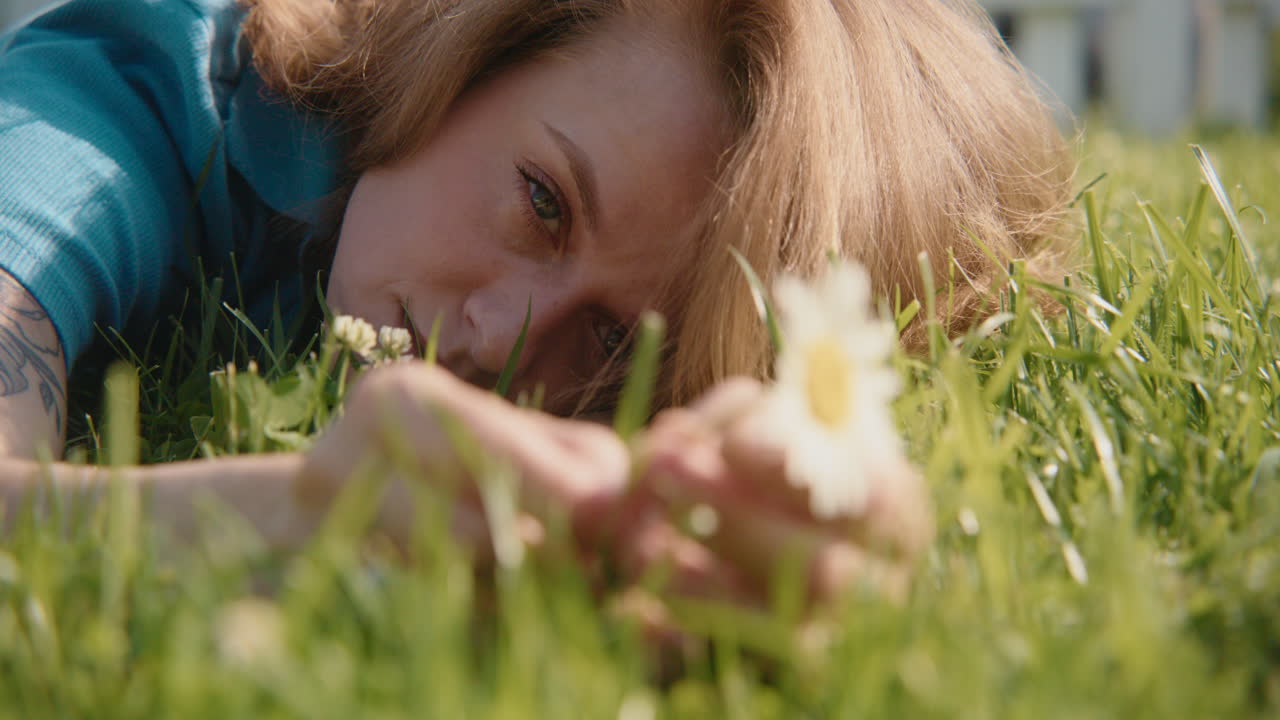Woman laying in grass holding a flower