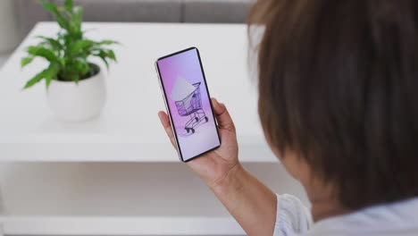 Biracial woman at home using smartphone for online shopping, slow motion