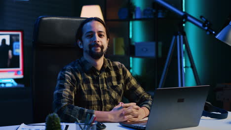 retrato de un hombre feliz sentado en el escritorio de la oficina de casa, resolviendo tareas en la computadora portátil