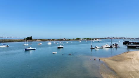 drone shot - flying over the water and filming anchored sail boats and comming in over land