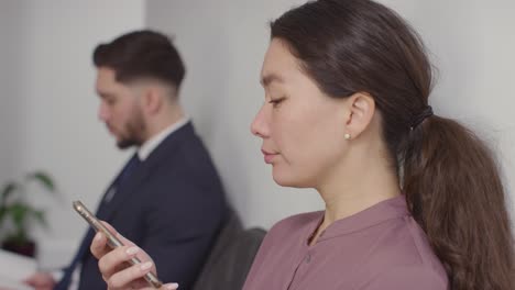 candidatos masculinos y femeninos en el cargo esperando una entrevista de trabajo mirando el teléfono móvil y leyendo notas 4