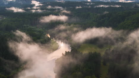 sigulda, latvia: morning mist (fog) over gauja national park. aerial birds eye rotation over the ancient river bringing life to 230 acres of lush green forest.