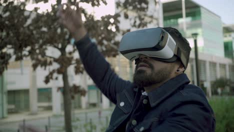 focused bearded man using vr glasses on street