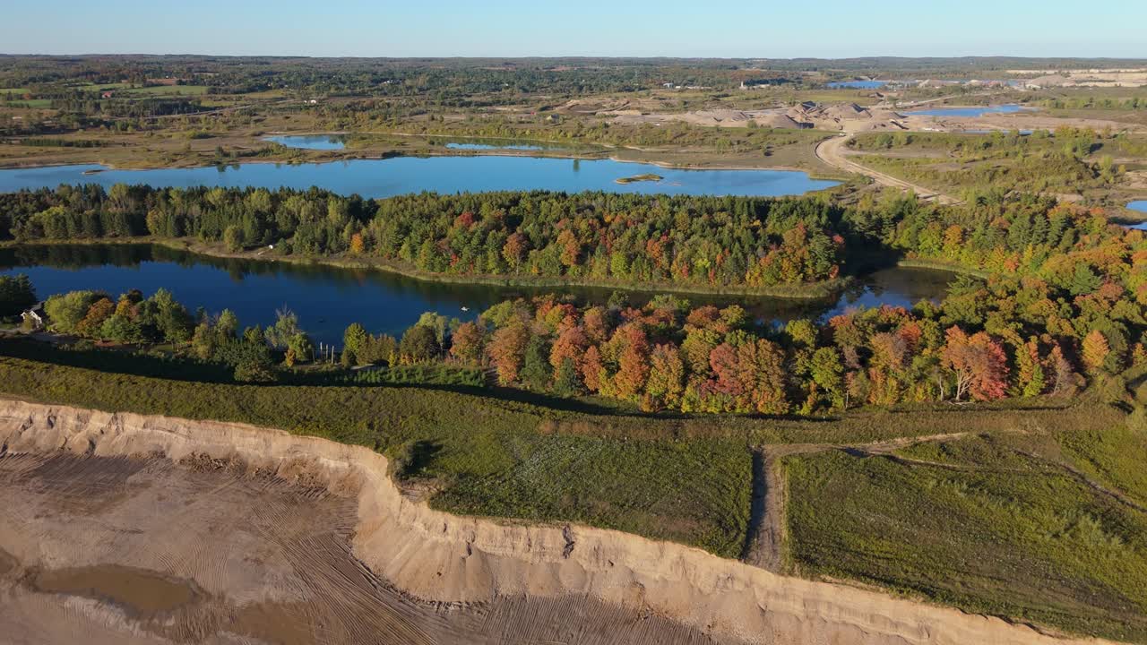Aerial view of a serene lake and lush trees, surrounded by a gravel pit