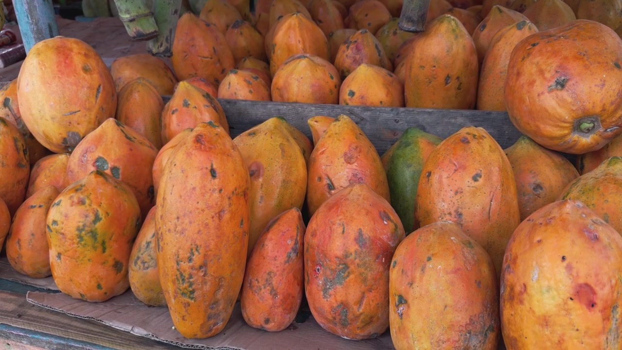 Grande mucchio di papaie fresche arancioni in mostra per la vendita al mercato di strada locale.