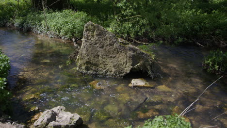 shot of a large rock in the stream that feeds the lake pond of creswell crags, worksop